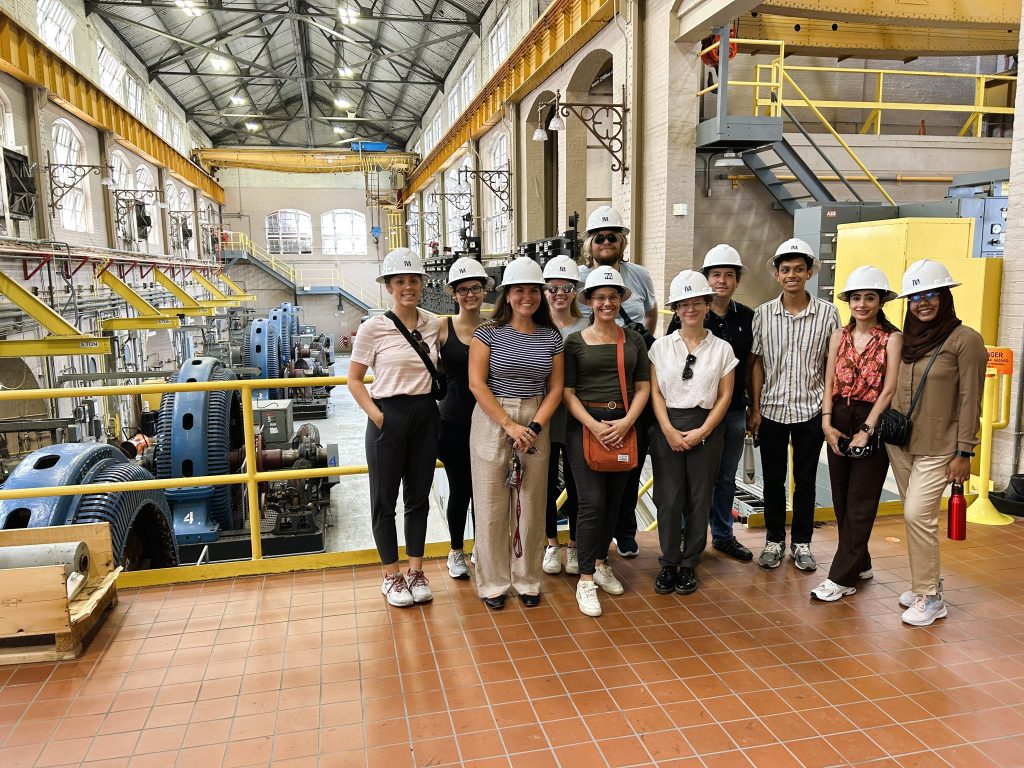 College students wearing hard hats and standing inside of a dam.