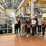 College students wearing hard hats and standing inside of a dam.