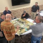 Emergency managers and local leaders gather around a large map, discussing potential flooding areas of concern.
