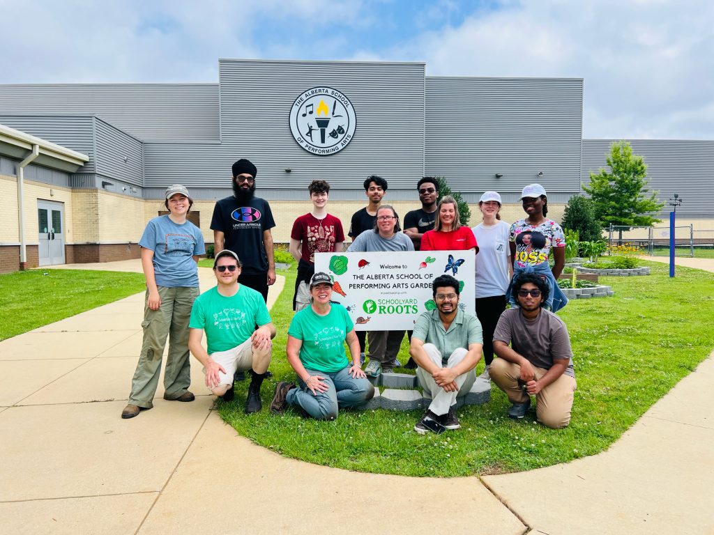 REU students posing outside of the Alberta School of Performing Arts, with the school and garden behind them.