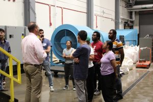 FLOW Academy participants engaged in discussion inside the USGS Hydrologic Instrumentation Facility, with equipment behind them.