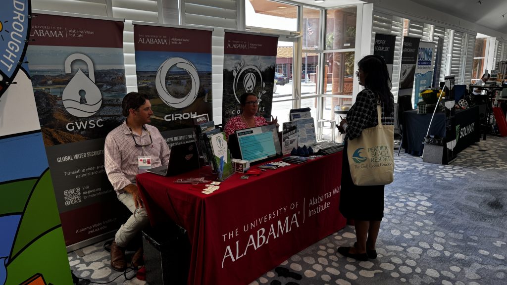 Conference attendees visiting the Alabama Water Institute table and spinning the Wheel of Water.