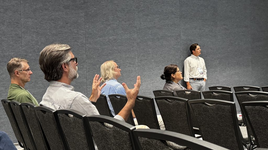 People sitting and listening in a crowded room.