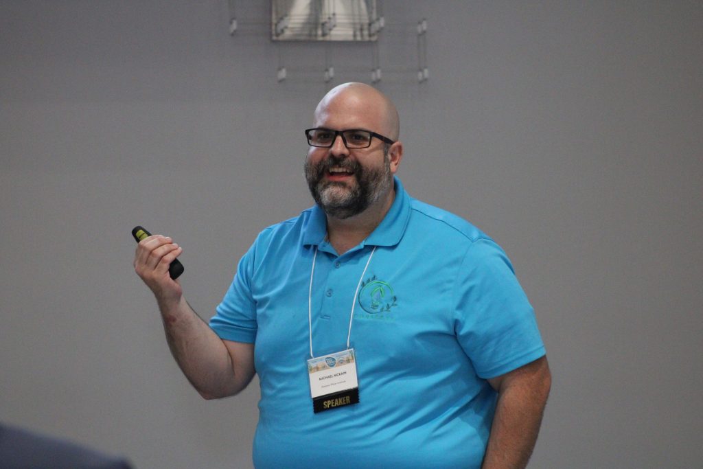 Person gesturing while delivering a conference presentation.