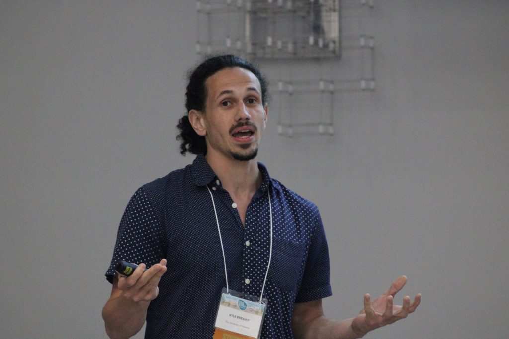 Person gesturing while delivering a conference presentation.