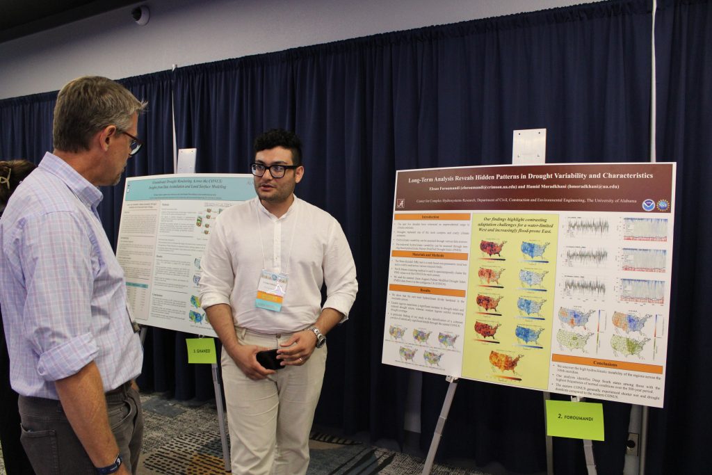 Presenters standing in front of their posters discussing their research.