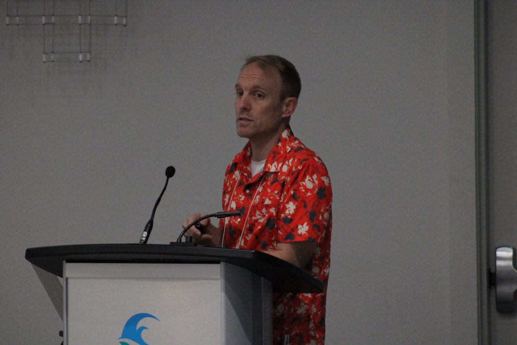 Person gesturing while delivering a conference presentation.