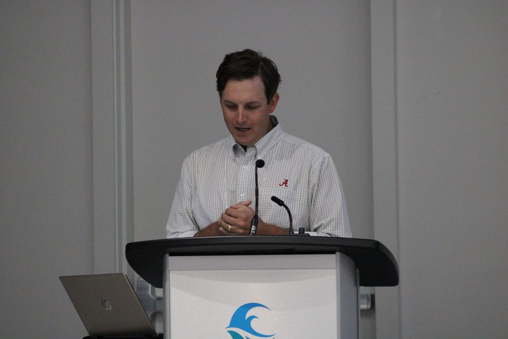 Person gesturing while delivering a conference presentation.