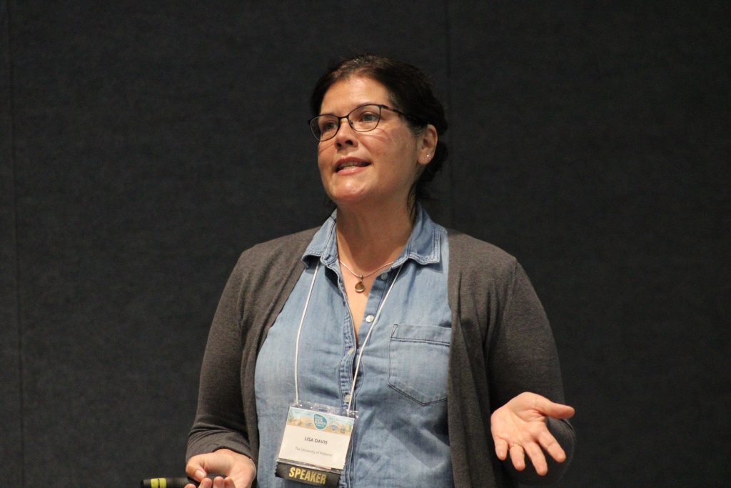 Person gesturing while delivering a conference presentation.