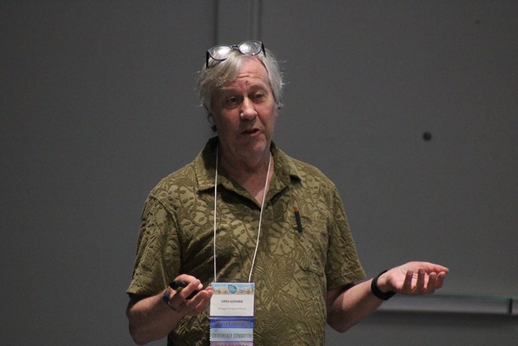 Person gesturing while delivering a conference presentation.