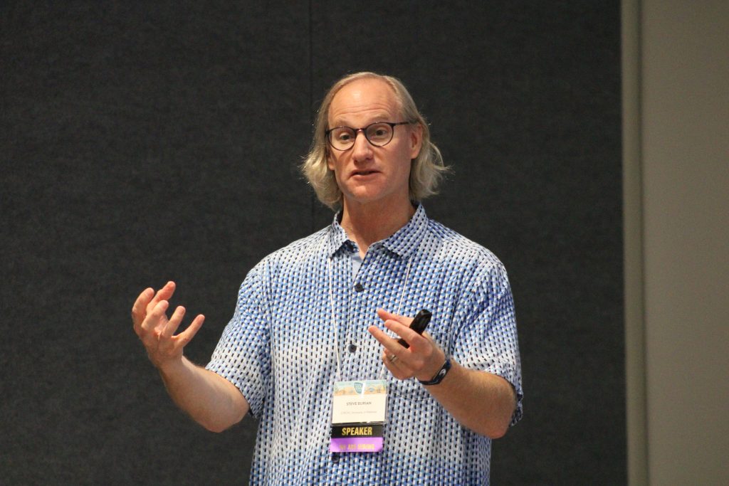 Person gesturing while delivering a conference presentation.