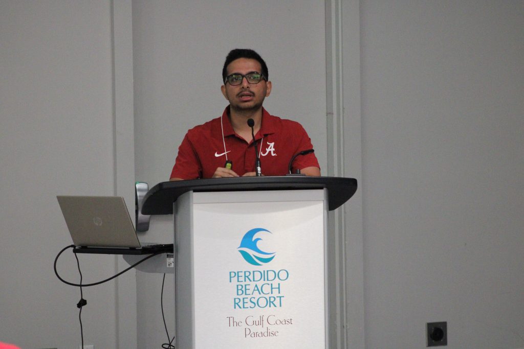 Person gesturing while delivering a conference presentation.