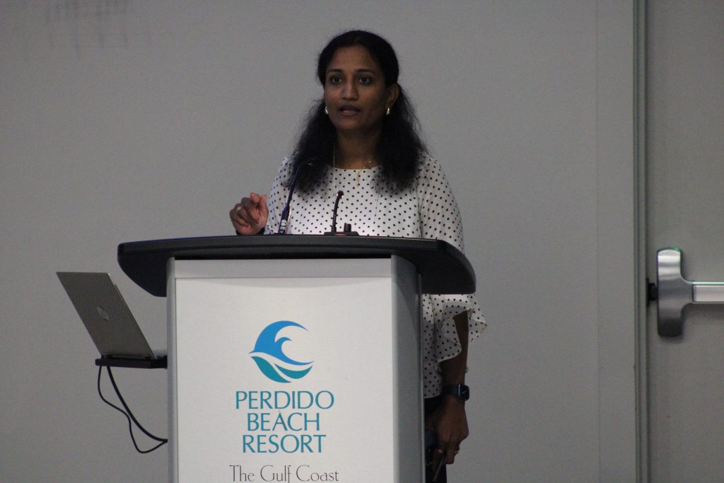 Person gesturing while delivering a conference presentation.