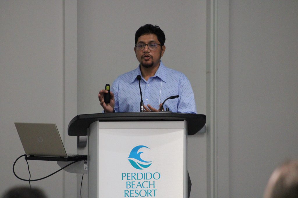Person gesturing while delivering a conference presentation.