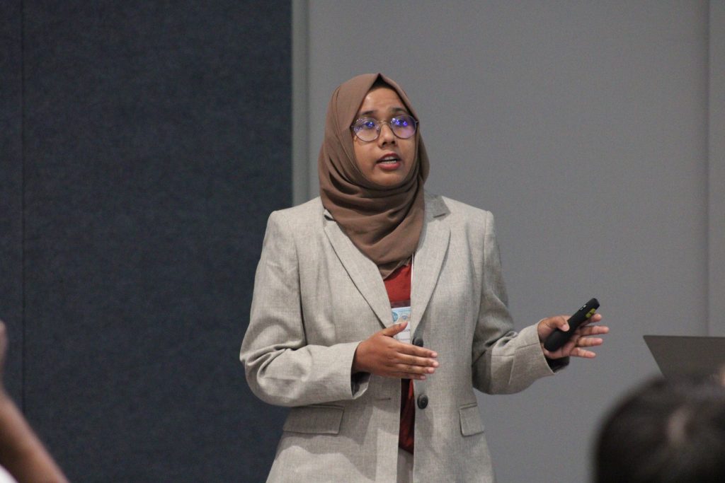 Person gesturing while delivering a conference presentation.