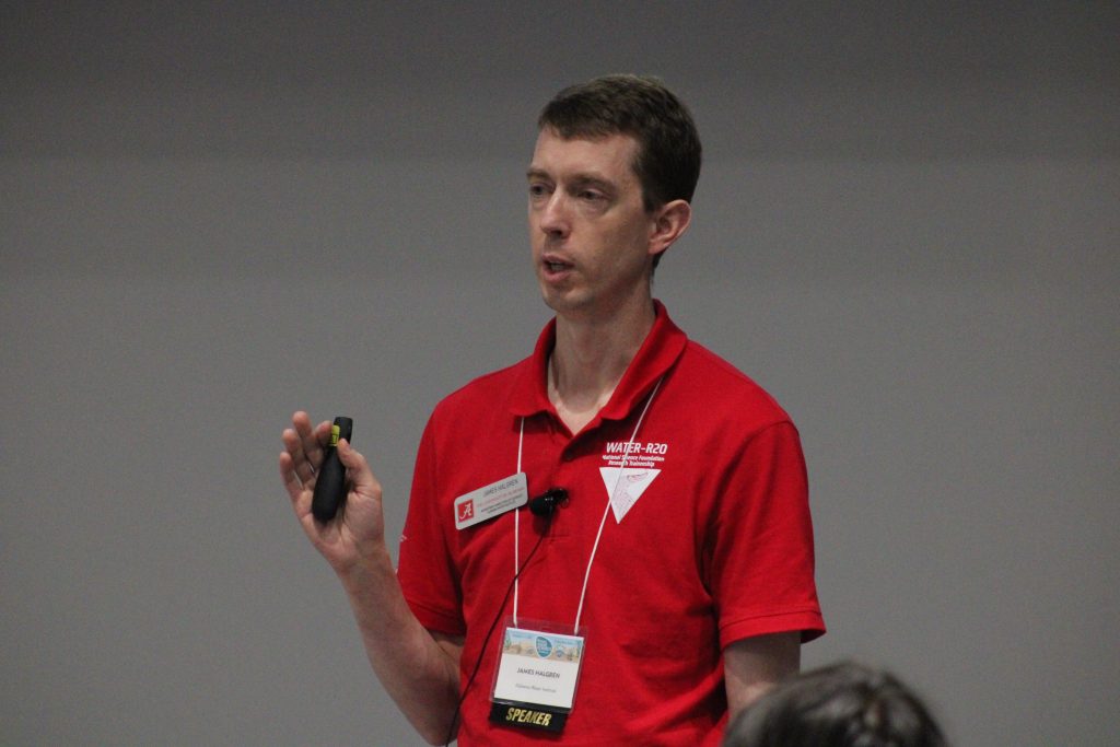 Person gesturing while delivering a conference presentation.