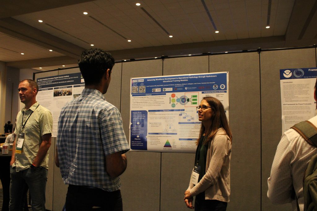 People in a conference hall gathered in front of research posters and engaged in discussion.