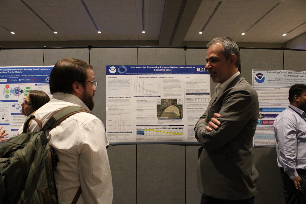 People in a conference hall gathered in front of research posters and engaged in discussion.