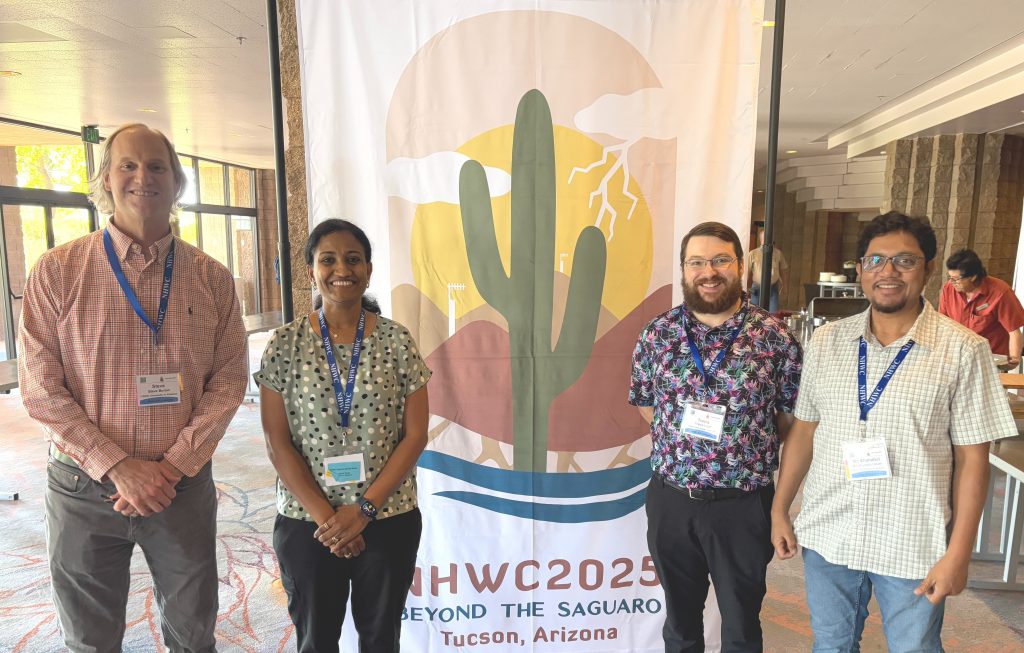 Four researchers stand together in front of a National Hydrologic Warning Council 2025 conference banner in Tucson, Arizona.