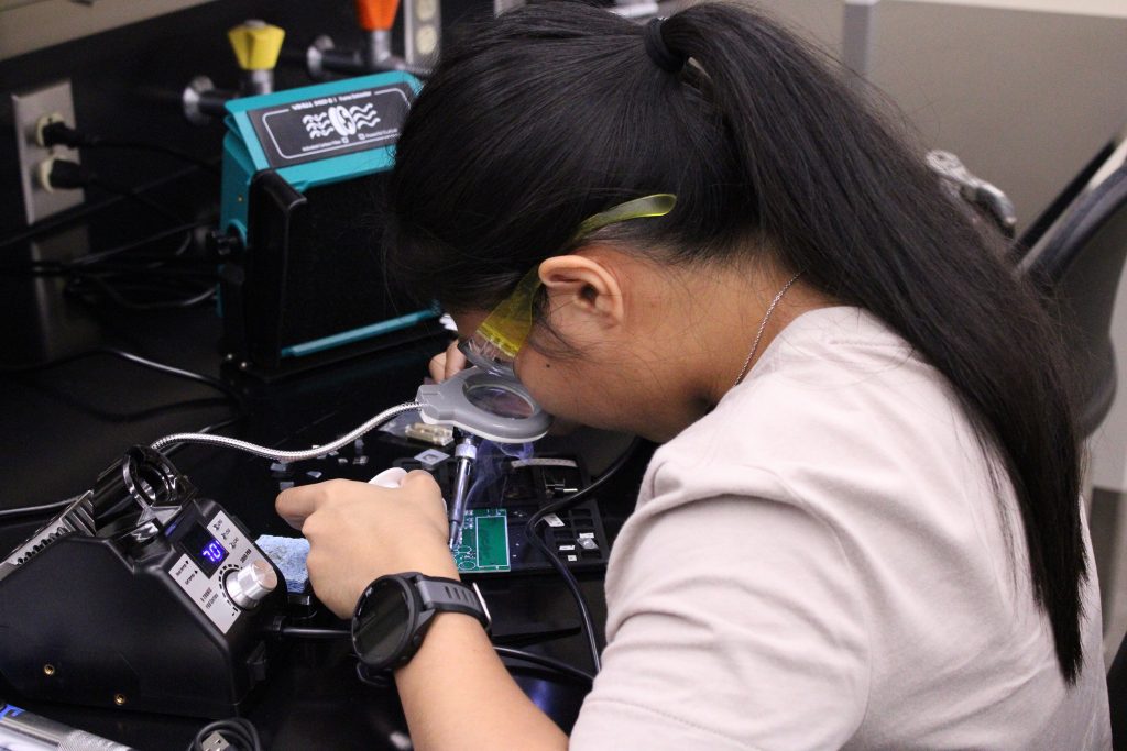 UA FLOW Academy students working with soldering equipment in University of Alabama engineering lab.