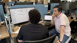 Researchers collaborating in a lab or office setting, using technology such as machine learning to address hydrological challenges.