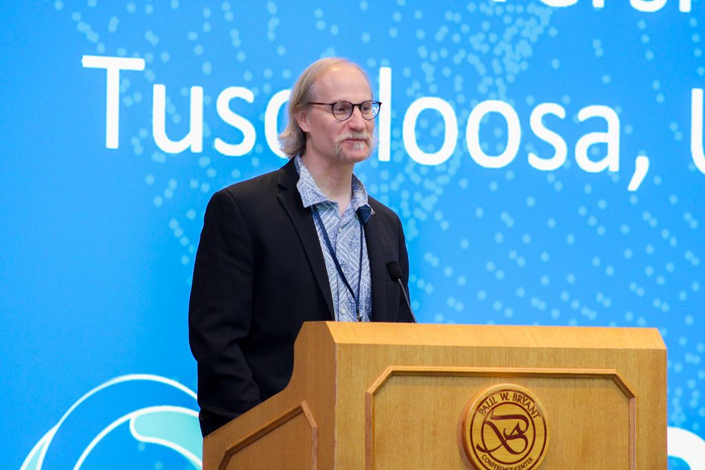 Man with horseshoe moustache and soul patch at podium.