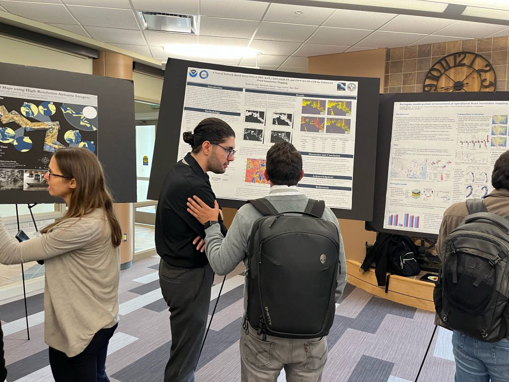 Three research posters and centered on a pair of attendees locked in discussion.