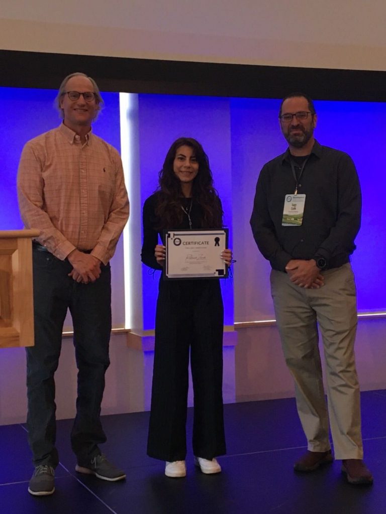 Reihaneh Zarrabi, center, holds her Early Career Paper Award certificate while standing with Steve Burian, left, and Sagy Cohen, right.